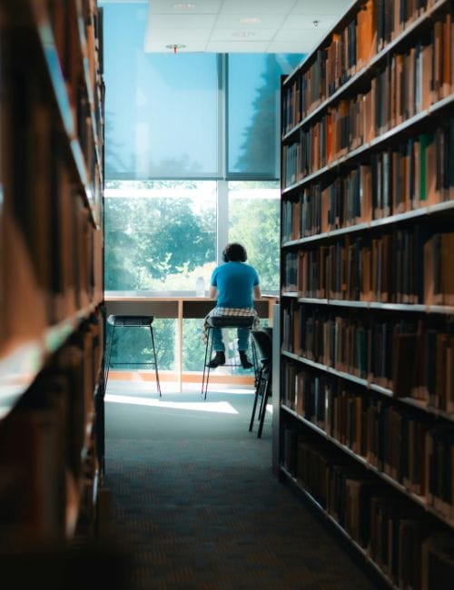 Une personne qui lit en fond dans une bibliothèque